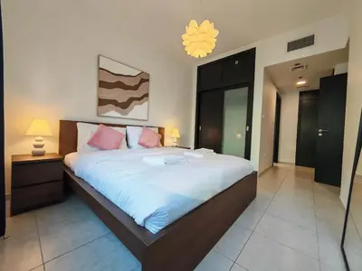 a bedroom with a large bed with white sheets and pink pillows at 1 Bedroom in Dubai Marina Walk, Partial Water View in Dubai