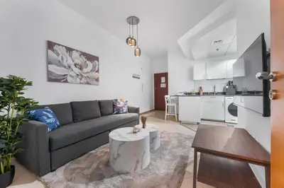 a living room with a couch and a table and a kitchen at StayShort - 1 Bed Apartment Sleeps 4 in Dubai Marina in Dubai