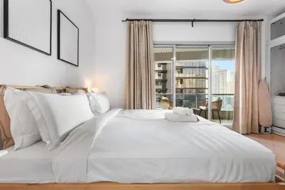 a bedroom with a large white bed with a window at StayShort - 1 Bed Apartment Sleeps 4 in Dubai Marina in Dubai