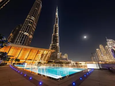 a large swimming pool in a city at night at Versace 1BR Downtown Burj View From Infinity Pool in Dubai