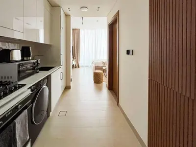 a hallway of a kitchen with a stove and a microwave at Luxe Studio Perch in Binghatti Azure with Pool & Gym in Dubai