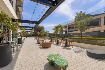 a patio with tables and chairs in a building at Cozy 2BR Apartment in Dubai Hills with Cinema and Lounge Access in Dubai