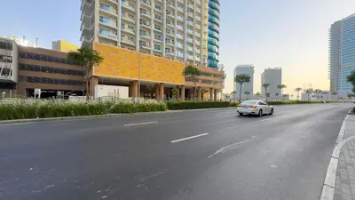 a white car driving down a street in a city at Stylish Apartment with Swimming Pool Near Dubai Mall and Burj Khalifa in Dubai