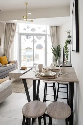 a dining room table with stools in a living room at Stylish Apartment with Swimming Pool Near Dubai Mall and Burj Khalifa in Dubai