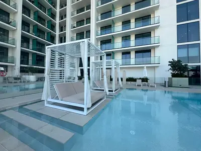 a couple of white chairs sitting on top of a pool at Restay Homes at Binghatti Azure - Great City Escape - Swimming Pool Access in Dubai