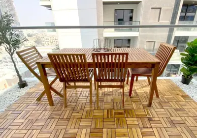 a wooden table and chairs on a balcony at Modern Studio Apartment with Balcony in JVC in Dubai