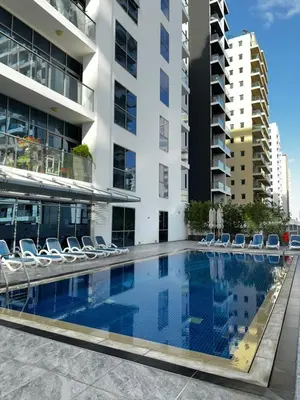 a swimming pool with lounge chairs and a building at Modern Studio Apartment with Balcony in JVC in Dubai
