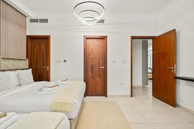 a bedroom with a large white bed and wooden doors at Stunning 2BR with Burj Lake View at The Residences in Dubai