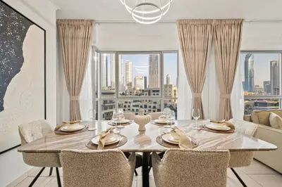 a dining room with a table and chairs and a large window at Stunning 2BR with Burj Lake View at The Residences in Dubai