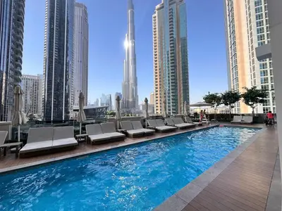 a swimming pool with chaise lounge chairs and a city skyline at 2BR next to Dubai mall with Khalifa Tower view! in Dubai
