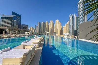 a swimming pool with chaise lounges and a city skyline at Waves - Modern Comfort 1BR Apt at JW Marriott Marina Mall in Dubai