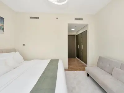 a white bedroom with a bed and a couch at 2BR Panoramic City - Burj and Fountain View in Dubai