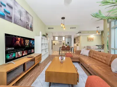 a living room with a couch and a tv at 2BR Panoramic City - Burj and Fountain View in Dubai