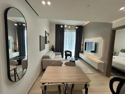 a living room with a couch and a table and a mirror at Chic 1bhk Smart Apartment, near circle Mall in Dubai