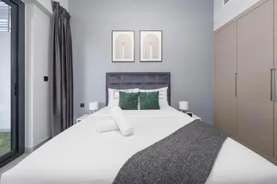 a bedroom with a large white bed with green pillows at Easy access to Community Parks and Green Spaces,15 minutes drive to Miracle Garden - Rigel, JVC, by Deluxe Holiday Homes in Dubai
