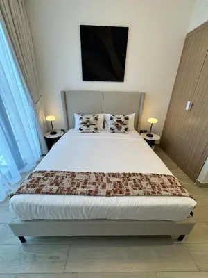 a large bed in a bedroom with two lamps at Beautiful Studio Brand New in Dubai