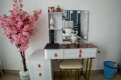 a dressing table with a vase of pink flowers at Bloom Tower B-Stunning View-Luxurious Furnish-Pool View in Dubai