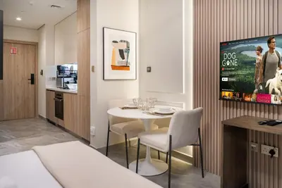 a room with a table and chairs and a kitchen at Stylish Modern Peninsula One Studio, Business Bay in Dubai