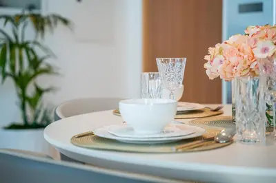 a white table with plates and cups and flowers on it at 2BR with Atlantis View, Beach Access, and Infinity Pool in Dubai
