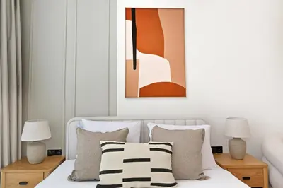 a bedroom with a bed with pillows and a painting at Aura by Grovy 405 - Parking, Pool&Gym - by Rentujemy in Dubai