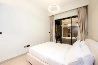 a white bedroom with a bed and a mirror at Venetian - Elegant 1BR in JVC & Perfect for Work Leisure in Dubai
