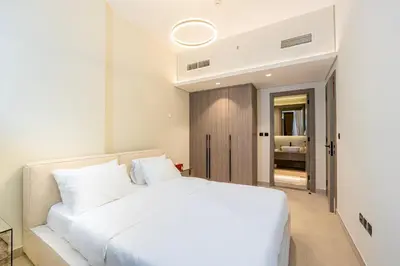 a bedroom with a white bed and a bathroom at Venetian - Elegant 1BR in JVC & Perfect for Work Leisure in Dubai