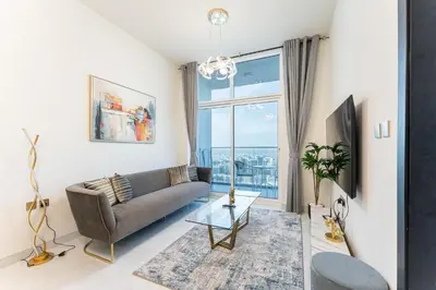 a living room with a couch and a large window at HAVN - 1 Bedroom in Skyz, 5 mins to Miracle Garden in Dubai