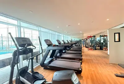 a gym with a row of treadmills and ellipticals at HAVN - 1 Bedroom in Skyz, 5 mins to Miracle Garden in Dubai
