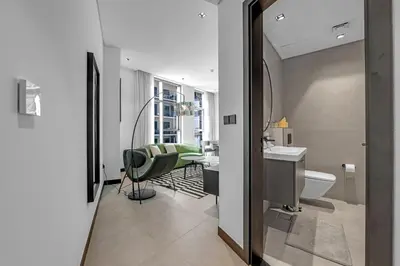 a bathroom with a sink and a toilet and a chair at Waves - Chic Business Bay 1BR - Bright and Modern in Dubai