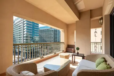 a balcony with a couch and chairs and a large window at Walnut Palm 2BR - Palm Jumeirah in Dubai