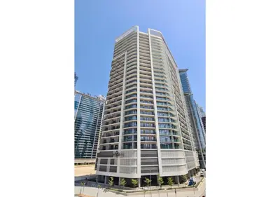 a tall white building in front of some buildings at KeyRock Living - Modern 1BR at Zada Tower with Pool and Gym Facilities in Dubai