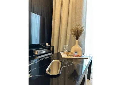 a living room with a tv and a glass table at KeyRock Living - Modern 1BR at Zada Tower with Pool and Gym Facilities in Dubai