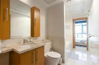 a bathroom with a toilet and a sink and a mirror at Stylish 1BR Retreat with Pool and Stunning City View in Dubai