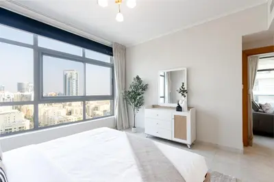 a white bedroom with a large window at Stylish 1BR Retreat with Pool and Stunning City View in Dubai