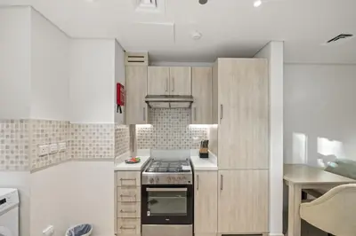 a kitchen with wooden cabinets and a stove at Seven Palm Elite 1BR-Infinity Pool & Skyline Views in Dubai