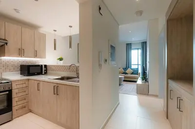 a kitchen with wooden cabinets and a living room at Stylish 1-BR Beachfront Apt on SEVEN PALM Dubai in Dubai