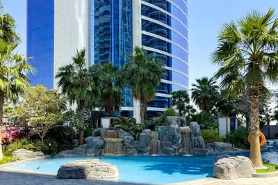 a fountain in front of a tall building with palm trees at Luxury Living at Paramount Tower B, Business Bay in Dubai
