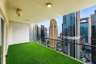 a balcony with green grass and a view of a city at Escape24 Luxury 2BR with Large Balcony and Lake Views in Dubai