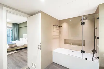 a bathroom with a tub and a bed in the background at Escape24 Luxury 2BR with Large Balcony and Lake Views in Dubai