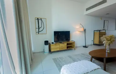 a living room with a tv and a table at 1BHK at Panoramic Tower, Marina with Sea and Canal View in Dubai