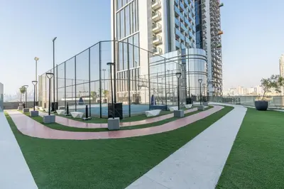 a large glass building with a green lawn in front of it at Samaya Holiday Homes - Cloud Stylish Suites with Balcony in Dubai