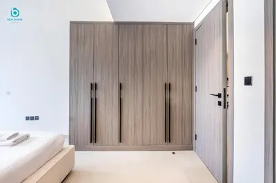 a bedroom with wooden cabinets and a bed at Blue Breeze Cozy 1 BR in JVC Al Serh Residence 11 in Dubai