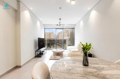 a living room with a table and white chairs at Blue Breeze Cozy 1 BR in JVC Al Serh Residence 11 in Dubai