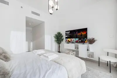 a white bedroom with a bed with a tv on the wall at 4Bedroom Luxury Stay in Downtown Views Dubai Mall in Dubai