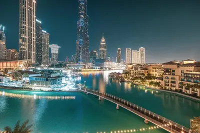 a view of a city at night with a river at Panoramic 4BR Burj Khalifa & Fountain View in Dubai