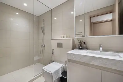 a white bathroom with a sink and a shower at Cozy 1Bedroom Apartment Downtown Dubai Retreat in Dubai