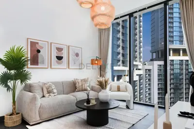a living room with a couch and a large window at Located Few Minutes Drive to Downtown Dubai, Burj Khalifa and Dubai Mall, Surrounded by Lush Green Community - Sobha Hartland The Crest Tower C by Deluxe Holiday Homes in Dubai