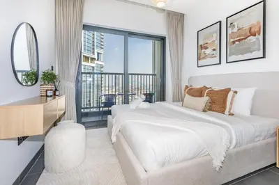 a white bedroom with a large bed and a balcony at Located Few Minutes Drive to Downtown Dubai, Burj Khalifa and Dubai Mall, Surrounded by Lush Green Community - Sobha Hartland The Crest Tower C by Deluxe Holiday Homes in Dubai