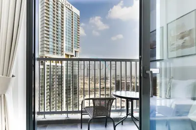 a balcony with a table and a view of a building at Located Few Minutes Drive to Downtown Dubai, Burj Khalifa and Dubai Mall, Surrounded by Lush Green Community - Sobha Hartland The Crest Tower C by Deluxe Holiday Homes in Dubai