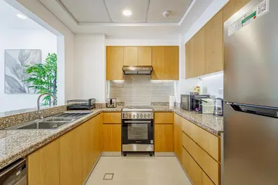 a kitchen with wooden cabinets and stainless steel appliances at Stunning Skyline Views and Prime Walkable Location in Dubai
